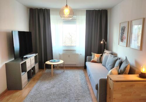 un salon avec un canapé bleu et une télévision dans l'établissement Apartment M - nice view, à Leipzig