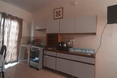uma cozinha com armários brancos e um forno com placa de fogão em El Hostal 57 em San Juan Opico