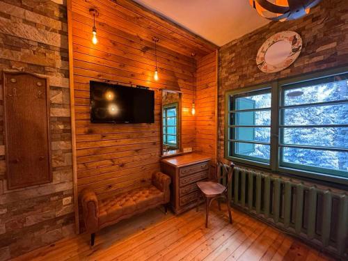 a room with a wooden wall with a television and a chair at Villa Adis with Hot Jacuzzi & Sauna in Borovets