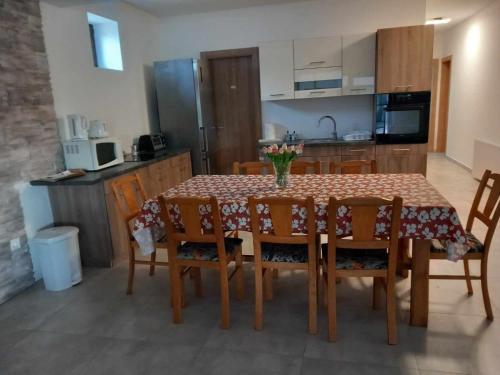 a dining room table with chairs and a kitchen at Avalon Vendégház in Levelek