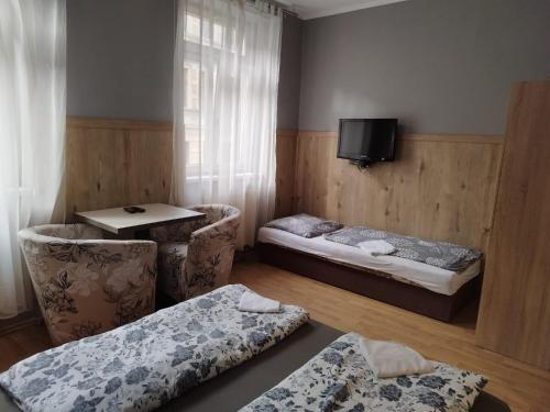 a room with two beds and a table and a tv at Apartments Manhattan in Teplice