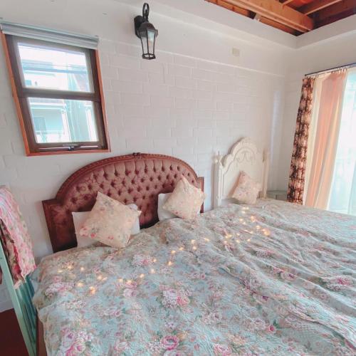 a bedroom with a large bed with a floral bedspread at 猫とピアノと星空のリゾートブティックコテージ -Starry Forest Cottage Okinawa- in Onna