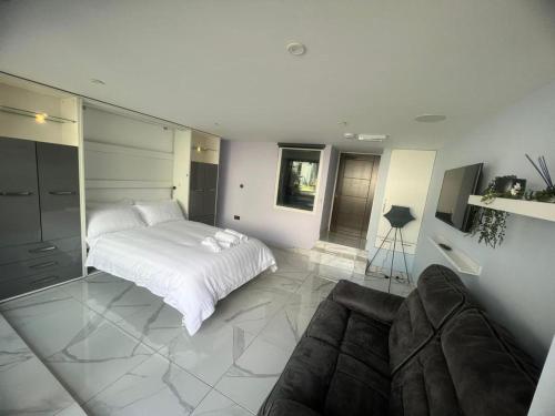 a white bedroom with a bed and a couch at Mara Boutique Apartments 1 in Oldbury