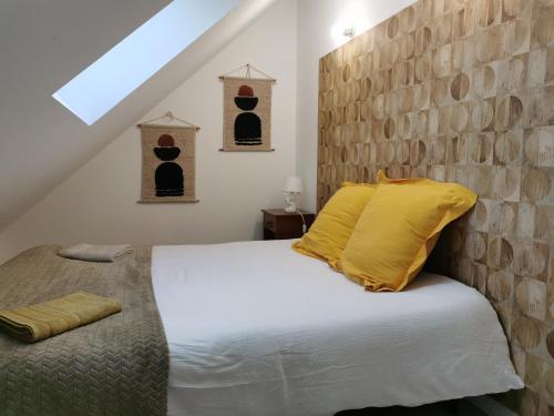 une chambre avec un lit blanc avec des oreillers jaunes dans l'établissement Les gîtes de L'hermine, à Plouigneau