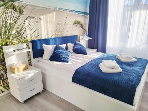 - une chambre avec un lit bleu et blanc et des oreillers dans l'établissement APARTAMENT MARI Polanki Park, à Kołobrzeg