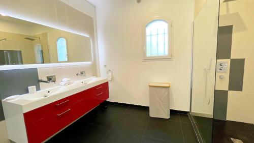 uma casa de banho com um lavatório vermelho e um espelho. em Villa des Chardonnerets em Mougins