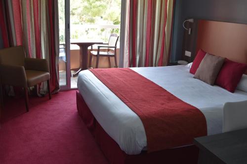 a hotel room with a large bed and a balcony at The Originals City, Le Mas de Grille, Montpellier Sud in Saint-Jean-de-Védas
