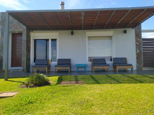 a patio with blue chairs and a wooden pergola at Casas Arena y Sol - FRENTE AL MAR in Parque del Plata