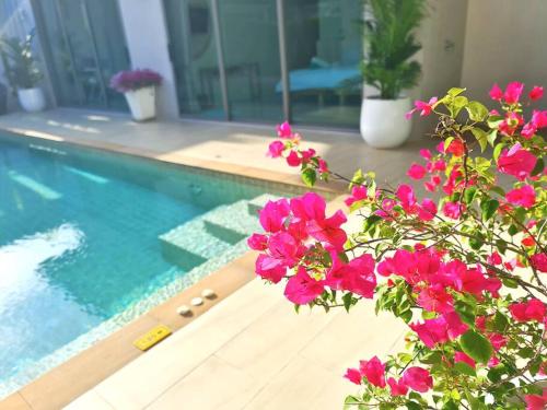 a plant with pink flowers next to a swimming pool at 拉威海滩 放松舒适的4卧室 泳池别墅 卡塔卡伦-查龙优越的地理位置 in Ban Kata