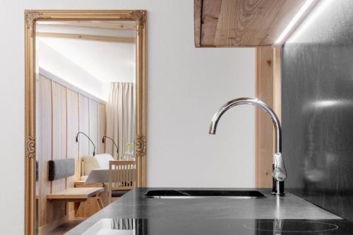 a kitchen with a sink and a mirror at Appartamenti Residence Ada in San Cassiano