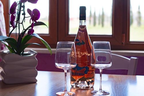 a bottle of wine sitting between two glasses on a table at Casale la Rovere in Montalto di Castro