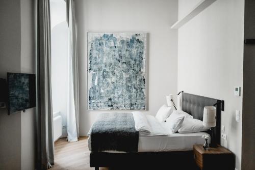 een slaapkamer met een bed met een schilderij aan de muur bij Small Luxury Hotel Altstadt Vienna in Wenen