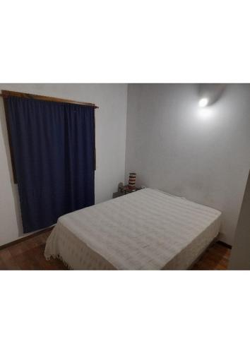 1 dormitorio con cama y cortina azul en Maxidepartamento en Miramar