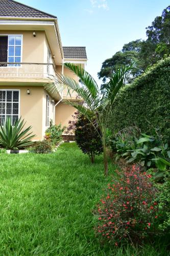 ein Haus mit einem grünen Garten mit einer Palme in der Unterkunft Kilimanjaro Accommodation in Msaranga