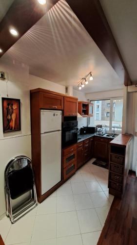 une cuisine avec des armoires en bois et un réfrigérateur blanc dans l'établissement Studio cosy 33 m² limite Lyon. Parking privatif., à Bron