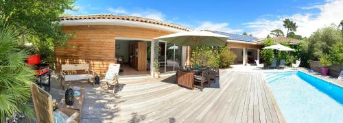 un patio avec un parasol et une piscine dans l'établissement Villa entre lac et océan, à Biscarrosse