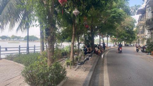 a group of people sitting on benches on the side of a street at Wins Apartment in Hanoi