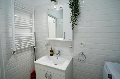 a white bathroom with a sink and a mirror at Modern & Comfortable Apartament Cismigiu Park - POP3 in Bucharest