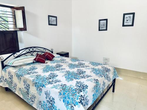 een slaapkamer met een bed met een blauwe en witte deken bij Malgudi House - Viceroy in Mysore