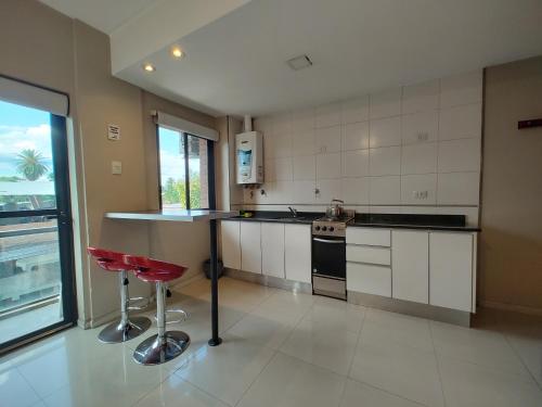 a kitchen with white cabinets and red stools at Shallor Cryss in San Miguel de Tucumán