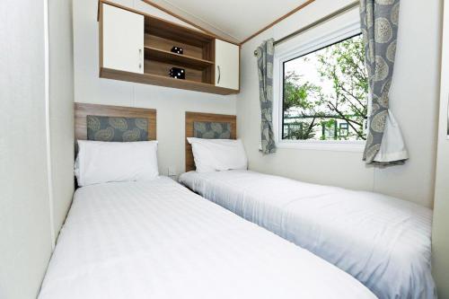two beds in a small room with a window at Mersea Island by Away Resorts in Colchester