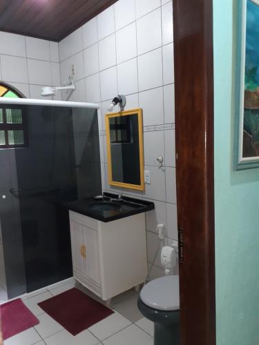 Un baño con lavabo y ducha con espejo. en Casa Curral, en Ilhabela
