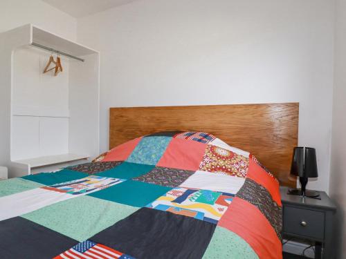 a bedroom with a bed with a colorful quilt on it at Lapwing in Perranporth