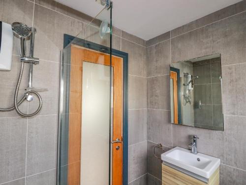 a bathroom with a shower and a sink and a mirror at Lapwing in Perranporth