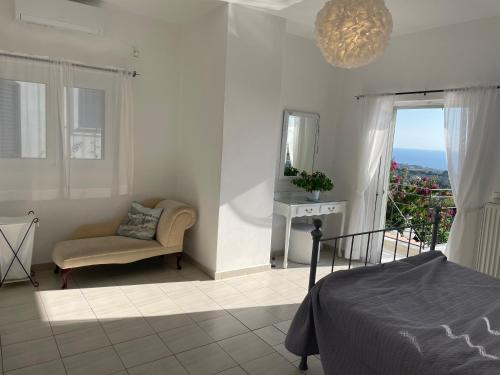 sypialnia z łóżkiem, krzesłem i oknem w obiekcie Villa Eleni w mieście Kefalonia