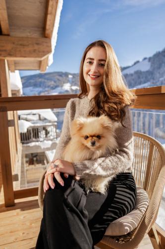 a woman sitting in a chair holding a small dog at Kellnergut Luxus-Chalet "FRIEDA" in Mühlbach am Hochkönig