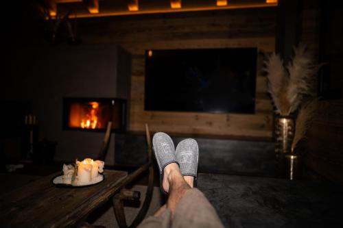 a person with their feet on a table in a room with a fireplace at Kellnergut Luxus-Chalet "FRIEDA" in Mühlbach am Hochkönig
