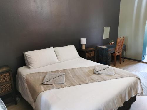 a bedroom with a white bed with two pillows on it at Karoozin Village in Oudtshoorn