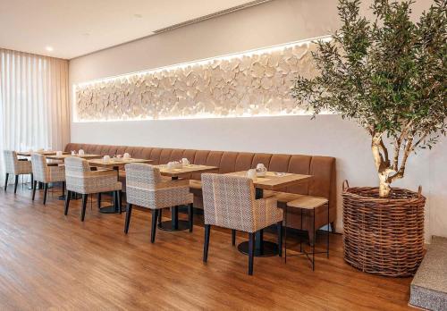 a restaurant with tables and chairs and a potted tree at Lamego Hotel & Life in Lamego