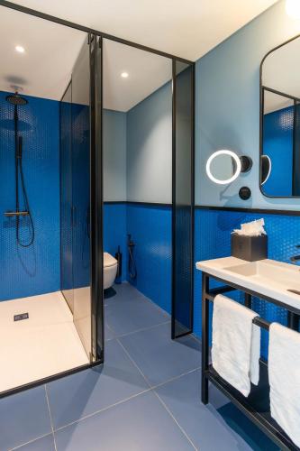 a blue bathroom with a shower and a sink at The Editory Riverside Hotel, an Historic Hotel in Lisbon