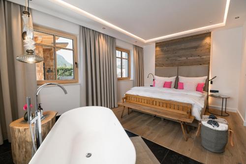 a bedroom with a bed with pink pillows and a tub at DAS SALZBERG Hideaway Bad Aussee - Adults only in Bad Aussee