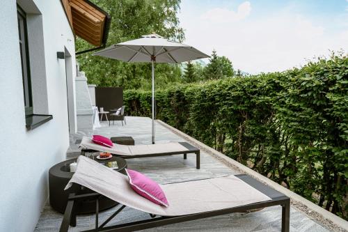 a patio with two chairs and an umbrella at DAS SALZBERG Hideaway Bad Aussee - Adults only in Bad Aussee