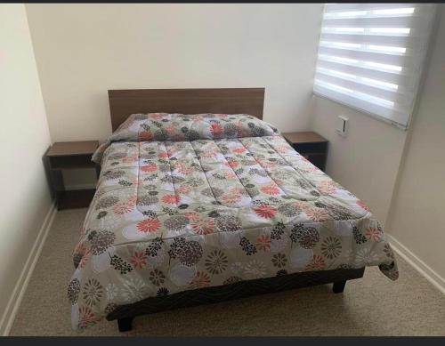 a bedroom with a bed with a quilt on it at Departamento Serena , La Florida in La Serena