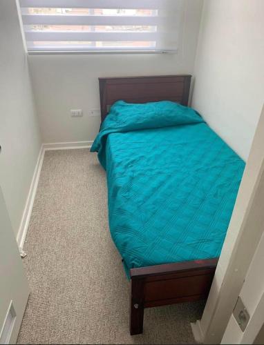 a small bedroom with a bed with a blue comforter at Departamento Serena , La Florida in La Serena