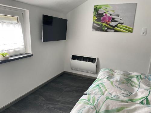 a bedroom with a bed and a tv on the wall at Ferienwohnung-Auszeit in Bad Harzburg