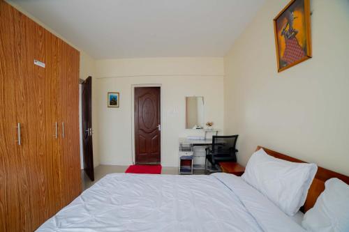 1 dormitorio con 1 cama y escritorio con ordenador en Airport Vista Getaway-4km from jomo Kenyatta International Airport, en Nairobi