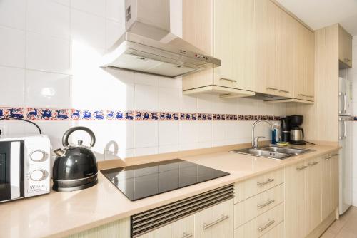 a white kitchen with a sink and a microwave at Apartamentos Blanes-Condal Costa Brava in Blanes