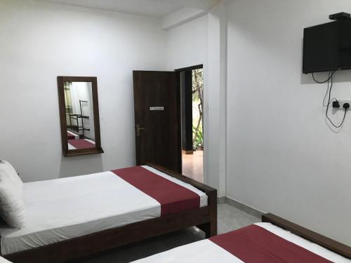 a bedroom with two beds and a mirror and a door at Nugasewana Guest in Anuradhapura