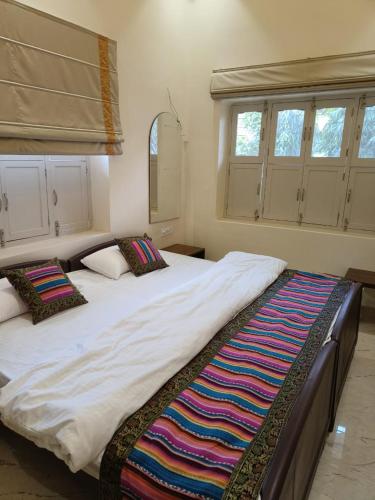 two large beds in a room with two windows at HERITAGE HAVELI VARANASI in Varanasi
