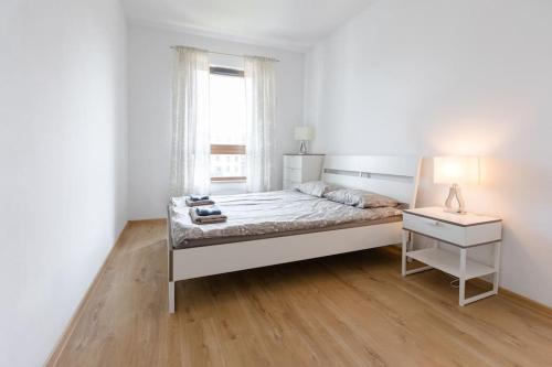 a white bedroom with a bed and a window at Apartament MioMare Letnica Seaside in Gdańsk