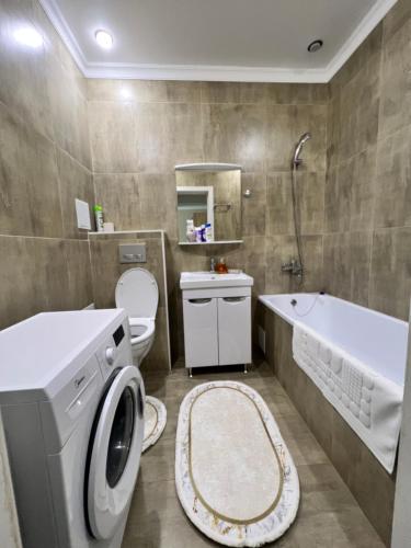 a bathroom with a washing machine and a toilet at Жк sezim Qala in Taldykolʼ
