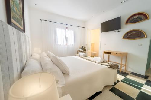 a white bedroom with a large white bed with a couch at Ca Sa Padrina d'Artà-Turismo de Interior in Artá