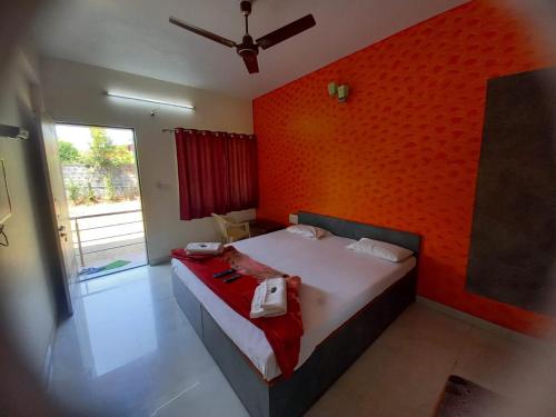 a bedroom with a bed with a red wall at Swami Leela Relax Inn in Mahabaleshwar