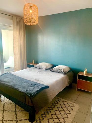 une chambre avec un grand lit avec un mur bleu dans l'établissement Bel appartement rénové proche Lyon, à Saint-Priest
