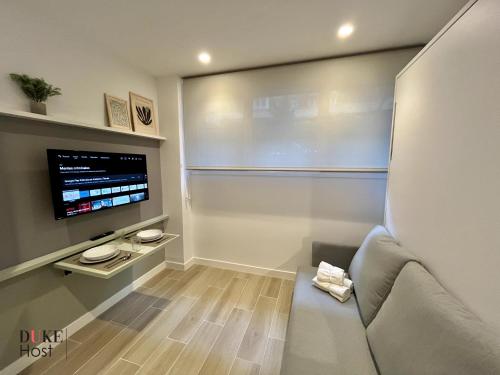 sala de estar con sofá y TV de pantalla plana en Duke Vallehermoso Apartament, en Madrid