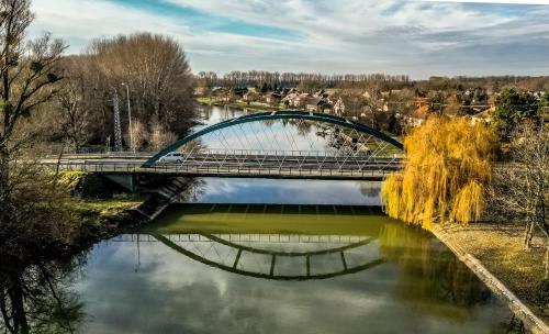 a bridge over a river with a reflection in the water at Regia Panzió in Halászi